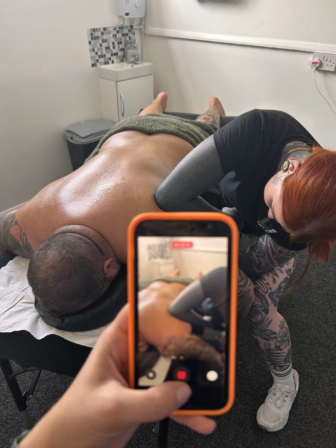 Looking over Amelia's orange phone as it records a therapist working on a client's back.